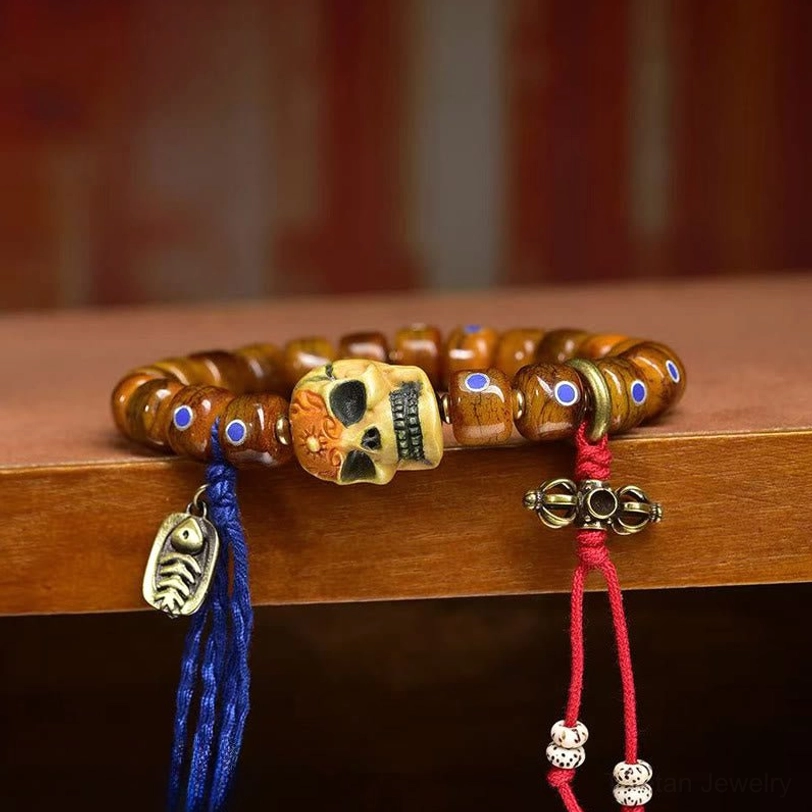 Close-up side view of Tibetan bone skull bracelet with inlaid beads and silver metal pendant