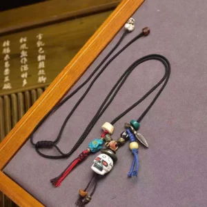 Tibetan skull Lord of Corpse Forest bone necklace pendant with braided cord and mixed agate beads - overhead angled view on wooden tray