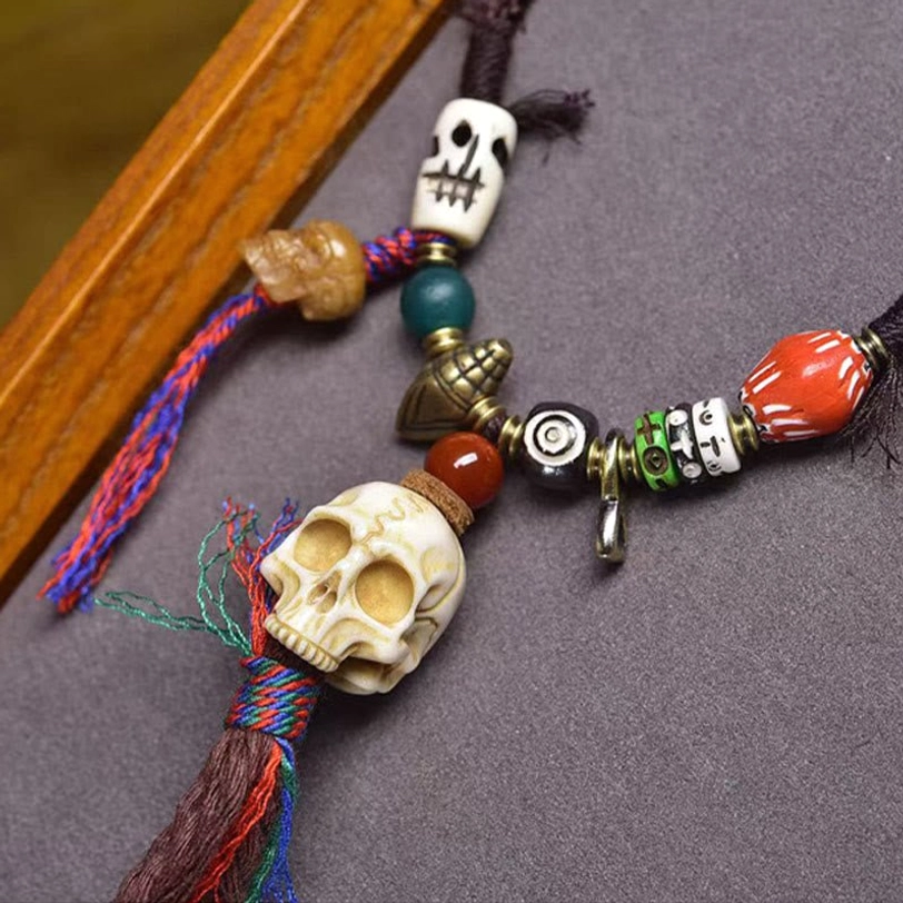 Close-up view of Tibetan Lord of the Corpse Forest bone skull necklace featuring large resin skull, brass spiritual charms, and mixed gemstone beads