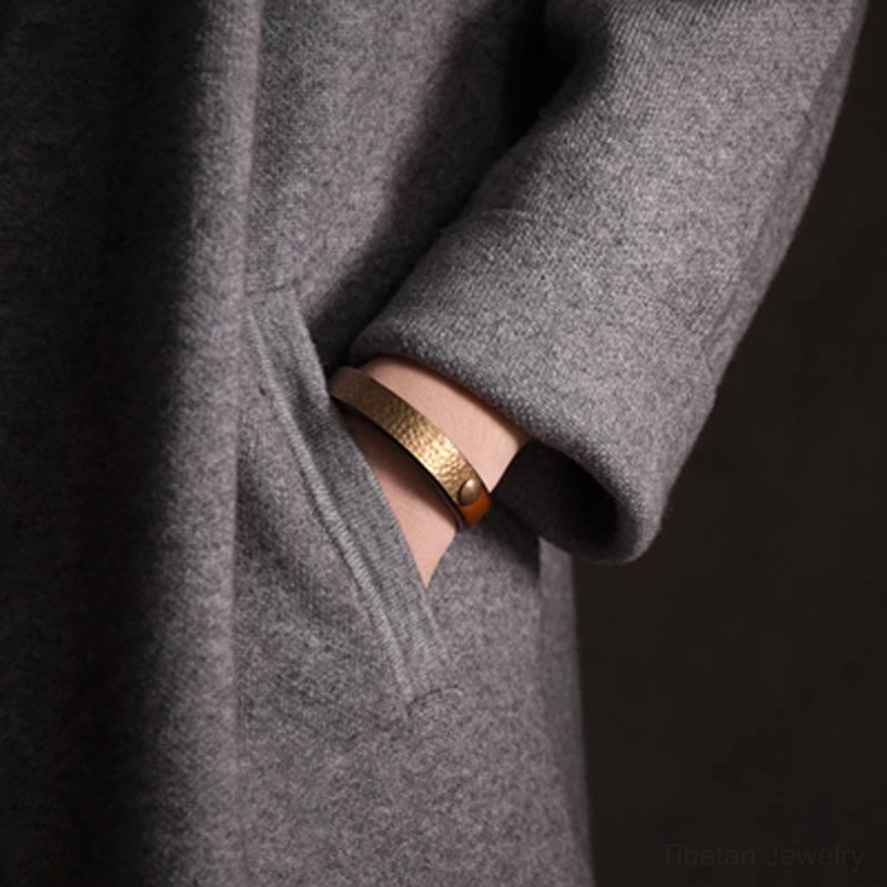 Slim solid brass Tibetan wealth bracelet with polished metal finish worn on wrist, minimalist design lifestyle wear