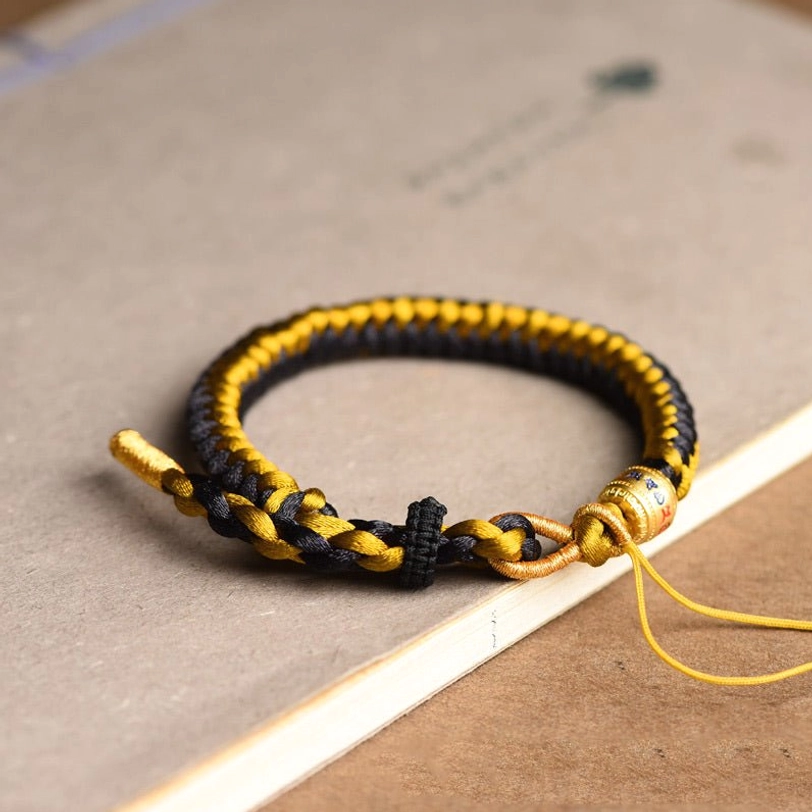 Tibetan om mani padme hum bracelet low angle showing metal charm bead and loose adjustable string design