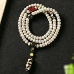 Star Moon Bodhi 108 prayer mala with Dzi bead bracelet, overhead view showing off-white spotted bodhi beads and striped protective Dzi pendant