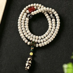 Star Moon Bodhi 108 prayer mala with Dzi bead bracelet, overhead view showing off-white spotted bodhi beads and striped protective Dzi pendant