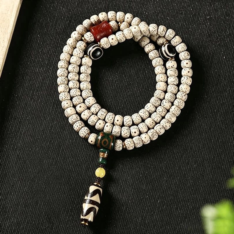 Star Moon Bodhi 108 prayer mala with Dzi bead bracelet, overhead view showing off-white spotted bodhi beads and striped protective Dzi pendant