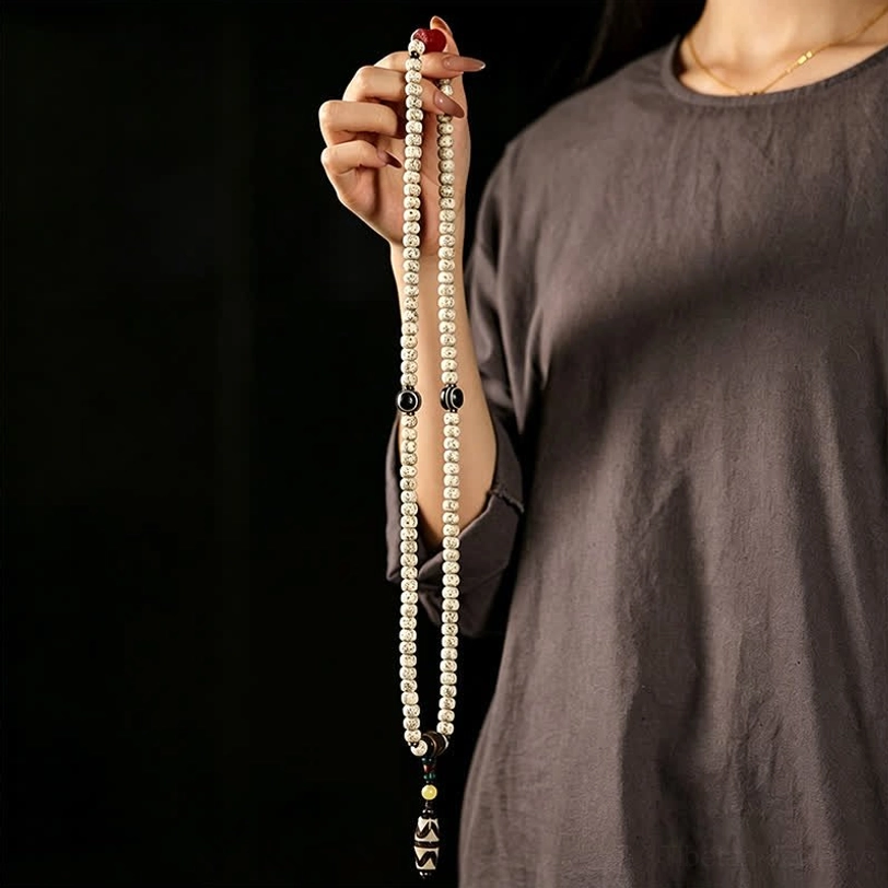 Long Tibetan star moon bodhi mala with Dzi pendant held vertically in hand, demonstrating full 108-bead prayer strand