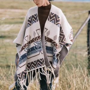 Ethnic geometric stripe shawl wrap with fringe trim displayed on model from front angle in grassland outdoor environment