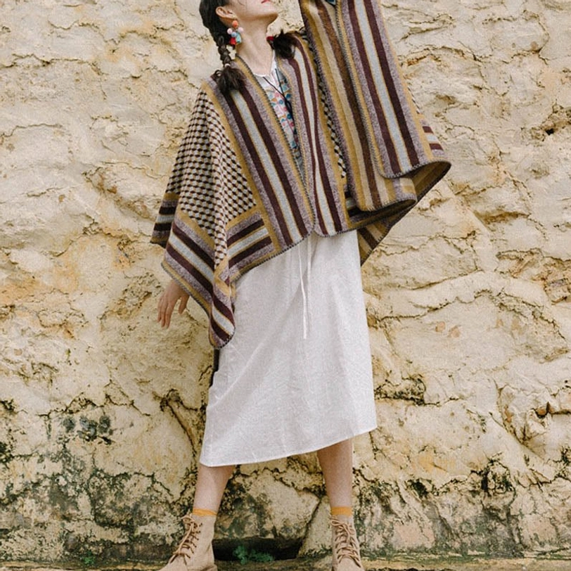 Side profile of Tibetan poncho shawl paired with white midi dress on stone wall backdrop, demonstrating relaxed styling