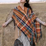 Tibetan striped tassel shawl with colorful geometric patterns displayed on grassland, front three-quarter view showing vibrant bohemian design