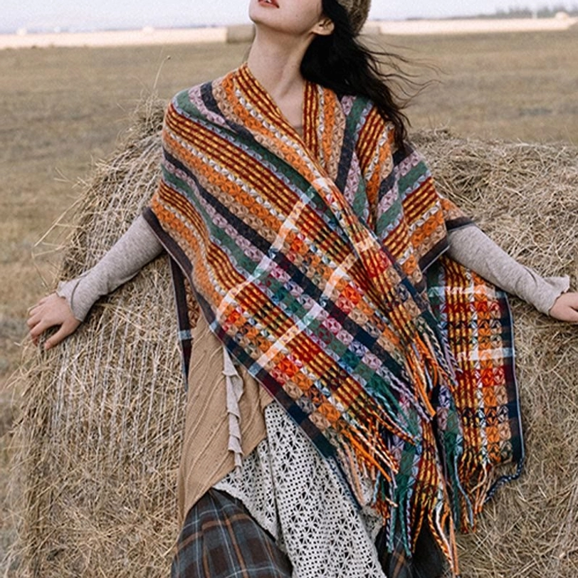 Tibetan striped tassel shawl with colorful geometric patterns displayed on grassland, front three-quarter view showing vibrant bohemian design