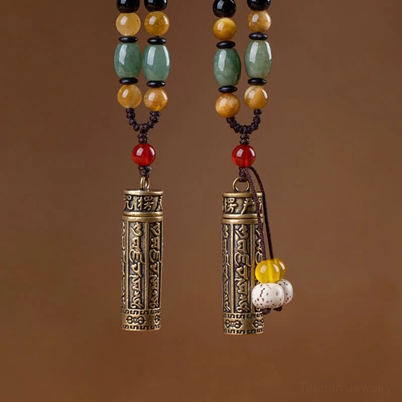 Close-up frontal view of Tibetan Om Mani Padme Hum necklace pendants with engraved brass cylinders and bodhi seed charms