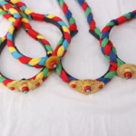 Tibetan colorful tassel hair clip with multicolor woven braids and copper decorative buckle - flat lay view