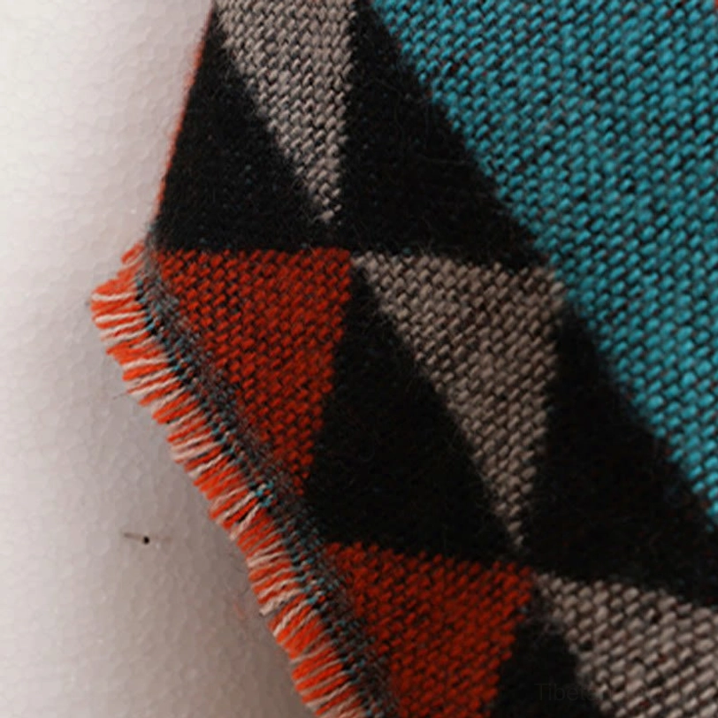 Back view detail of Tibetan tassel shawl showing geometric triangle patterns and authentic hand-tied fringe construction