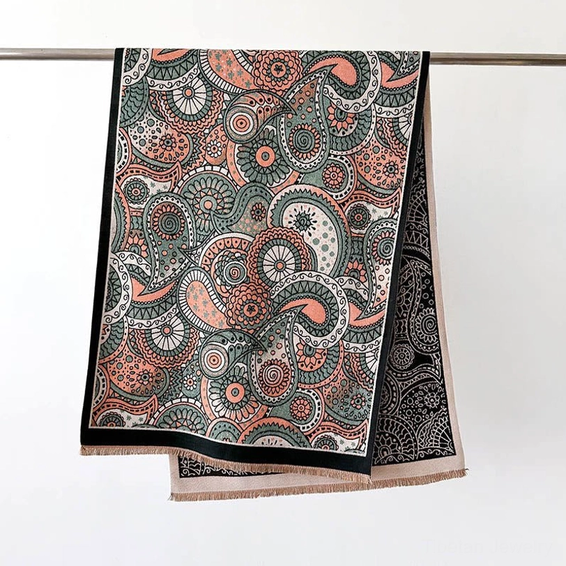 Tibetan ethnic tassel shawl flat lay hanging on metal rod, displaying double-sided reversible paisley print and fringed bottom edge on white background