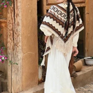 Tibetan geometric knit tassel shawl worn on shoulders, brown and beige striped pattern, rear full-body view against vintage wooden doorway