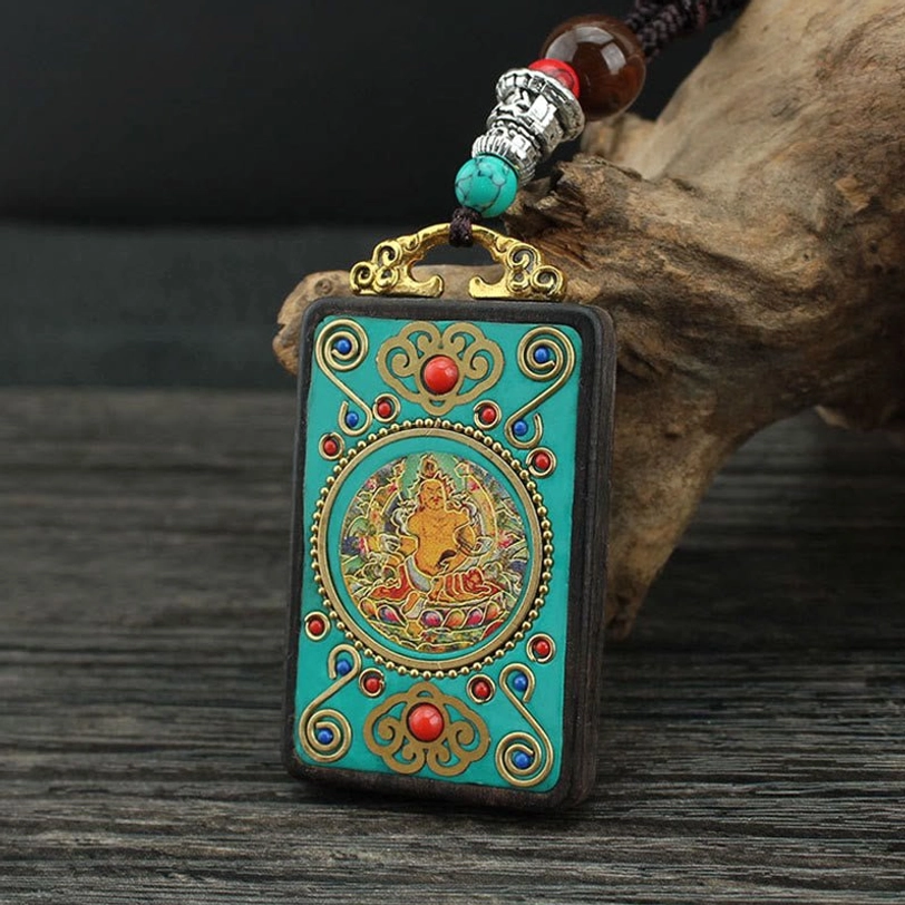 Tibetan thangka pendant necklace with turquoise Buddha design, gold filigree details, and beaded hardware on wooden driftwood backdrop
