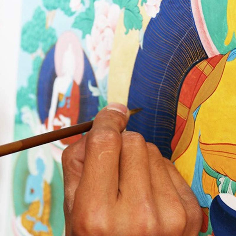 Tibetan artist hand-painting Buddhist mandala thangka artwork with fine brush in traditional studio workspace