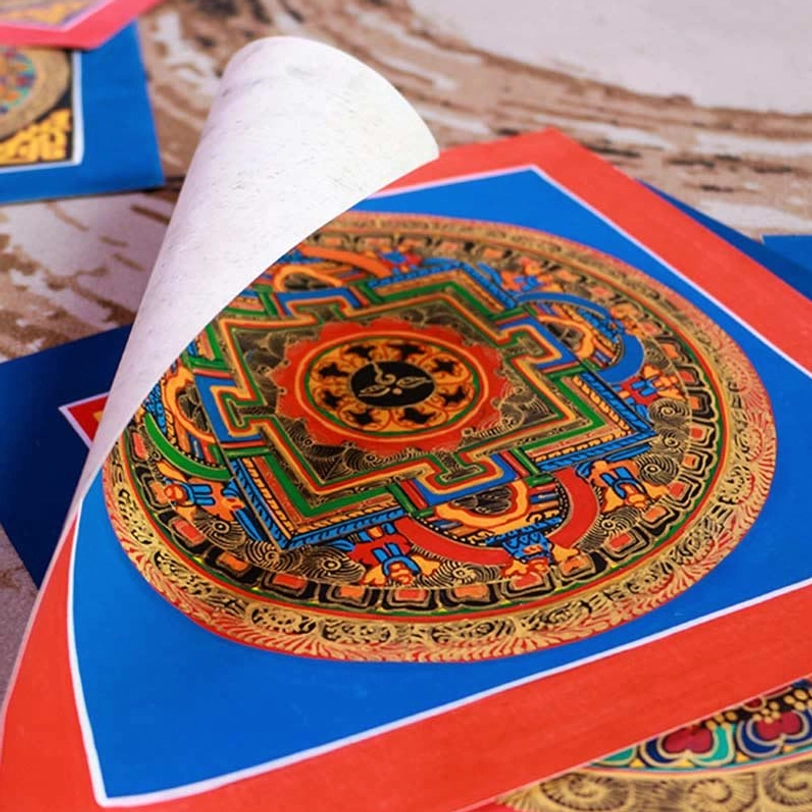 Tibetan mandala thangka unfolded square format with blue-red border and intricate gilt religious patterns from side angle