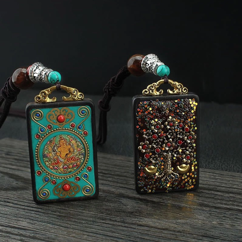 Pair of Five Gods of Wealth Thangka pendant necklaces with turquoise Buddha motif and gold decorative elements on beaded string, overhead view on dark wooden surface