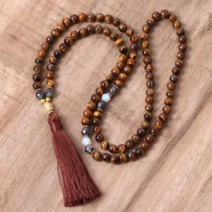 Tiger eye Buddha mala necklace flat lay with burgundy tassel and gold hardware on wooden surface