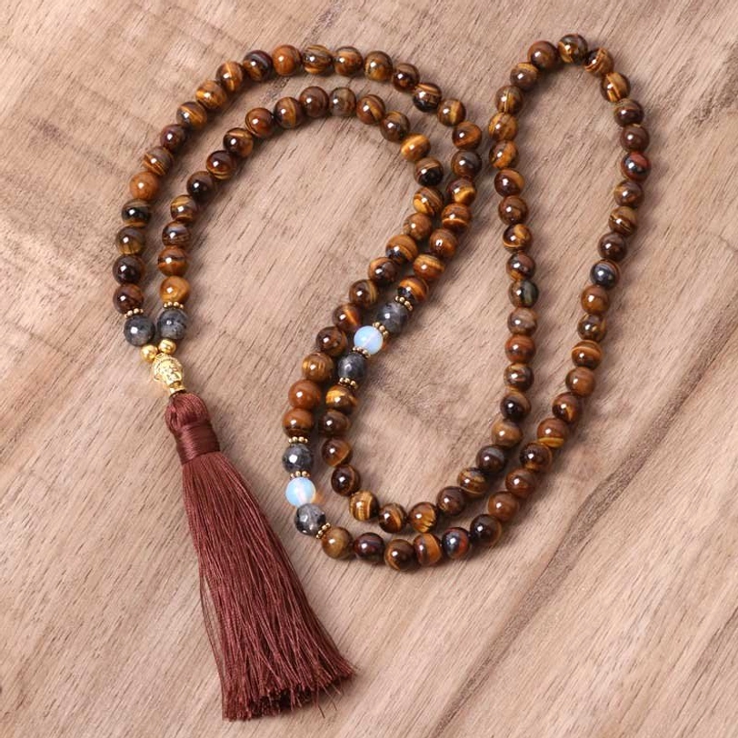 Tiger eye Buddha mala necklace flat lay with burgundy tassel and gold hardware on wooden surface