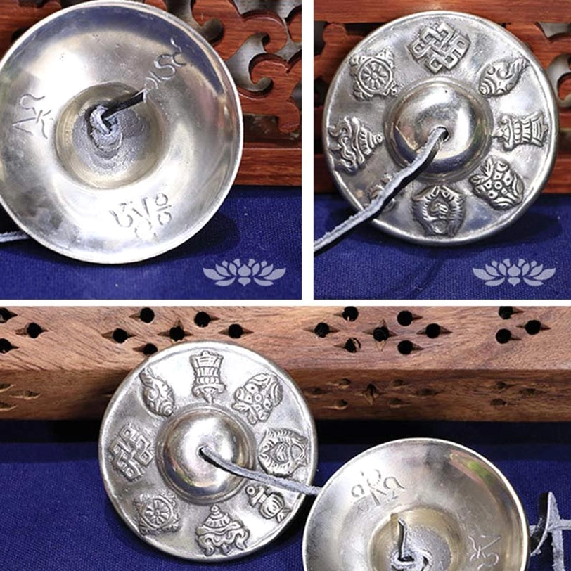 Two views Tibetan tingsha bells silver-toned copper inner engraved auspicious symbols side and front overhead carved wood blue fabric