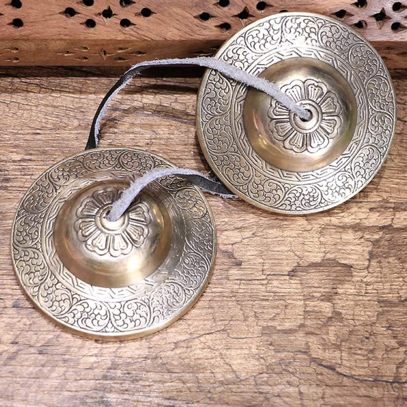 Tibetan tingsha bells pair copper cymbals om mani padme hum engraved top view wooden surface