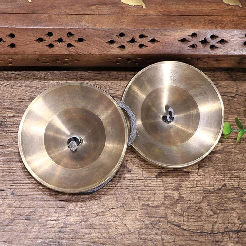 Pair of plain polished brass tingsha cymbals flat lay leather connecting loops