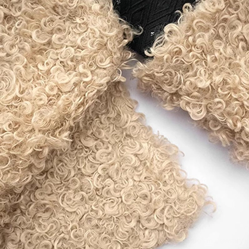 Close-up flat lay of thick curly beige fleece interior lining of Tibetan winter top with irregular hem and black dotted fabric
