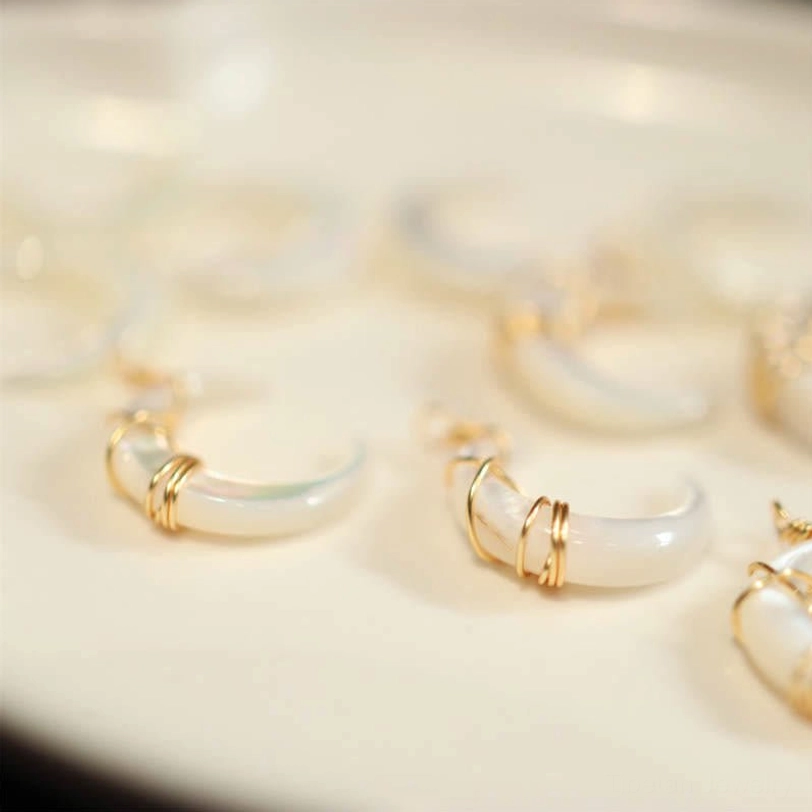 Unassembled Tridacna crescent moon pendants flat lay showing gold wire wrapped shells on white display surface