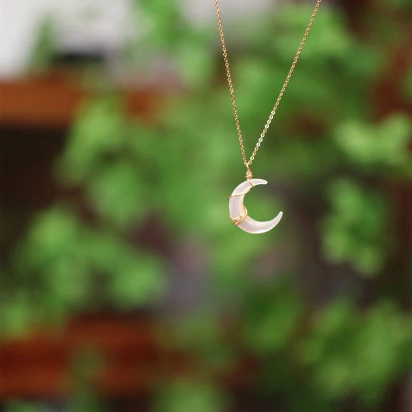 Delicate Tibetan crescent moon Tridacna necklace hanging with green plant background, showcasing pendant size