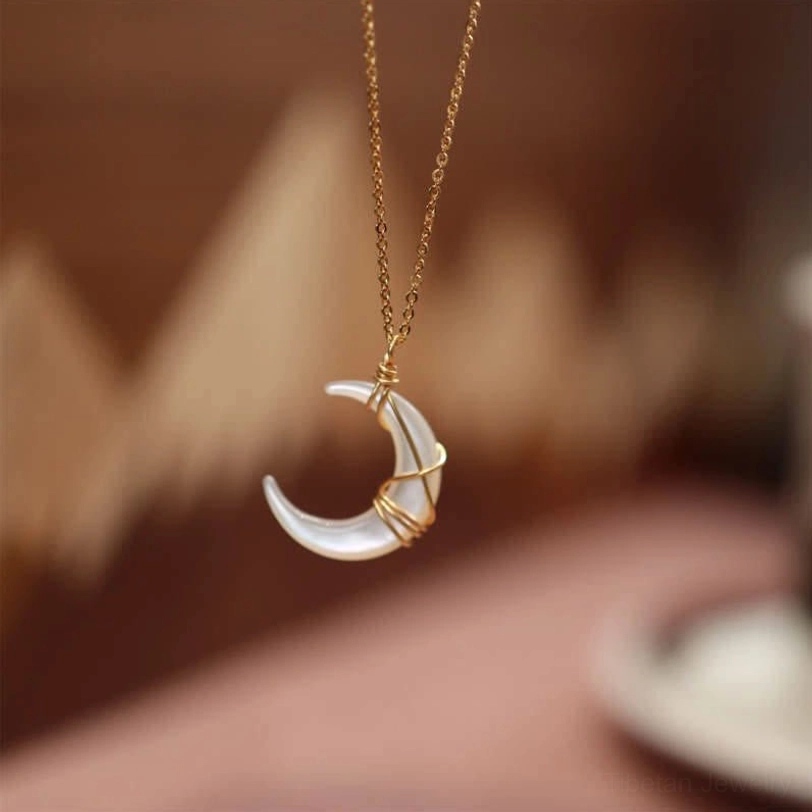 Tibetan Tridacna crescent moon pendant necklace in white iridescent stone with gold wire wrapping, front close-up view showing detailed craftsmanship