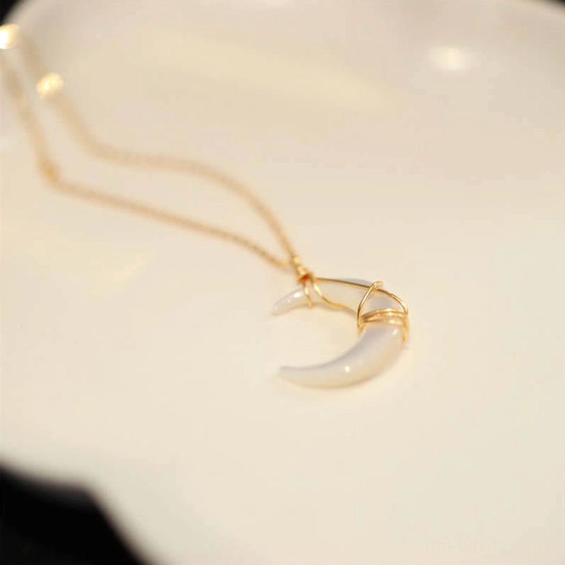 Tibetan Tridacna crescent pendant side view on white background showing delicate gold chain and wire wrapped stone