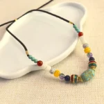 Tibetan handmade turquoise beaded necklace pendant with mixed gemstone beads and gold copper accents on white tray