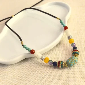 Tibetan handmade turquoise beaded necklace pendant with mixed gemstone beads and gold copper accents on white tray