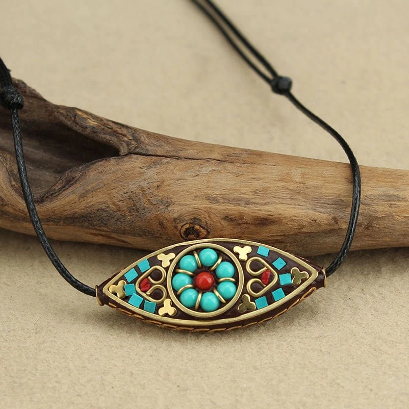 Close-up front view of Tibetan turquoise marquise pendant showing detailed red floral inlay and ethnic patterns