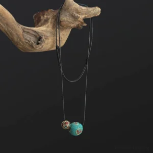 Tibetan turquoise throat chakra necklace hanging on driftwood against dark background, displaying adjustable black wax cord