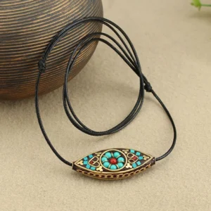 Handmade Tibetan turquoise pendant with antique copper frame and adjustable black cord, coiled display