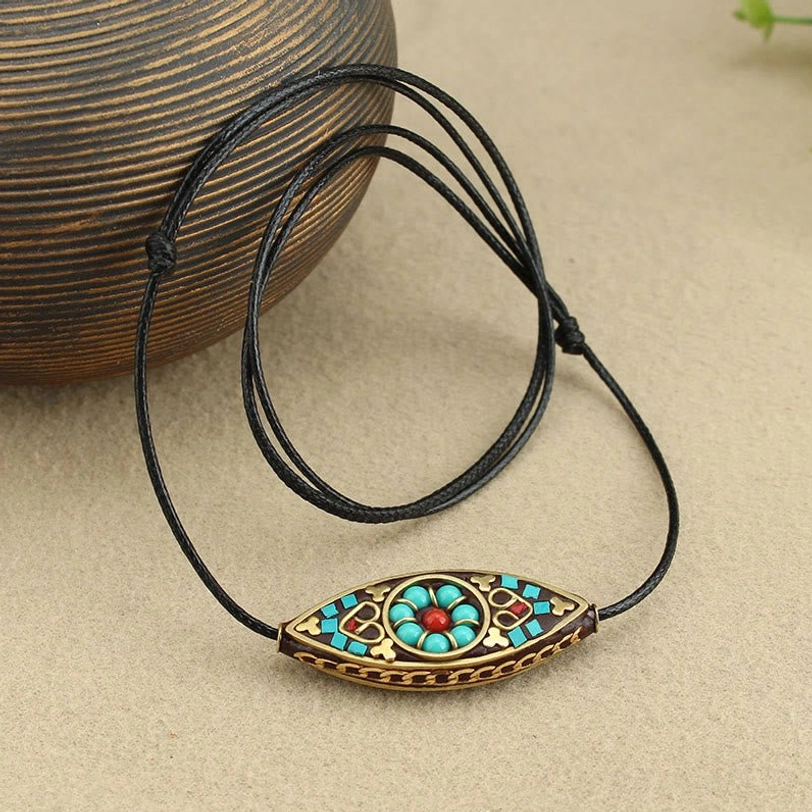 Handmade Tibetan turquoise pendant with antique copper frame and adjustable black cord, coiled display