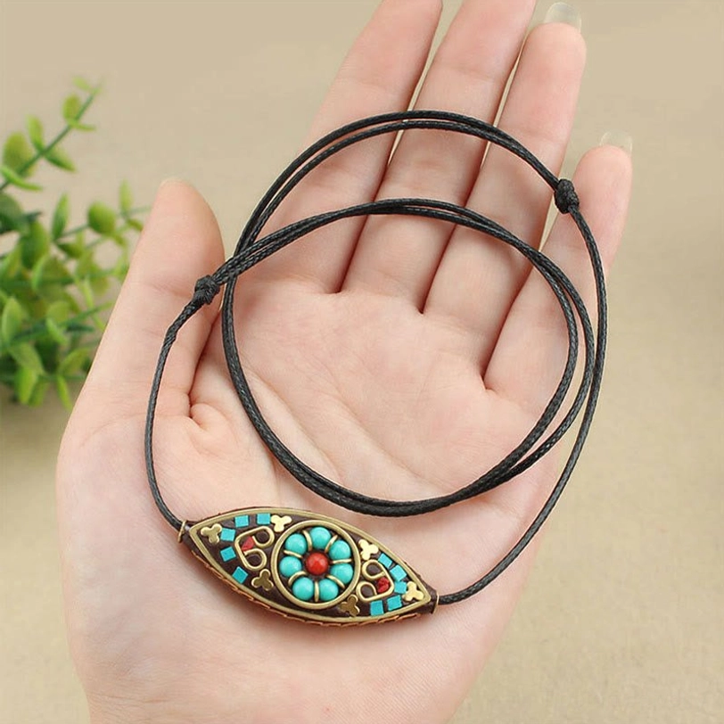 Tibetan turquoise pendant held in hand showing marquise shape and authentic ethnic front design detail