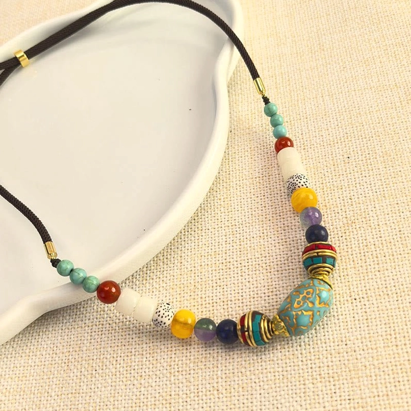 Tibetan turquoise stone necklace with adjustable black cord and varied gemstone spacers flat lay view