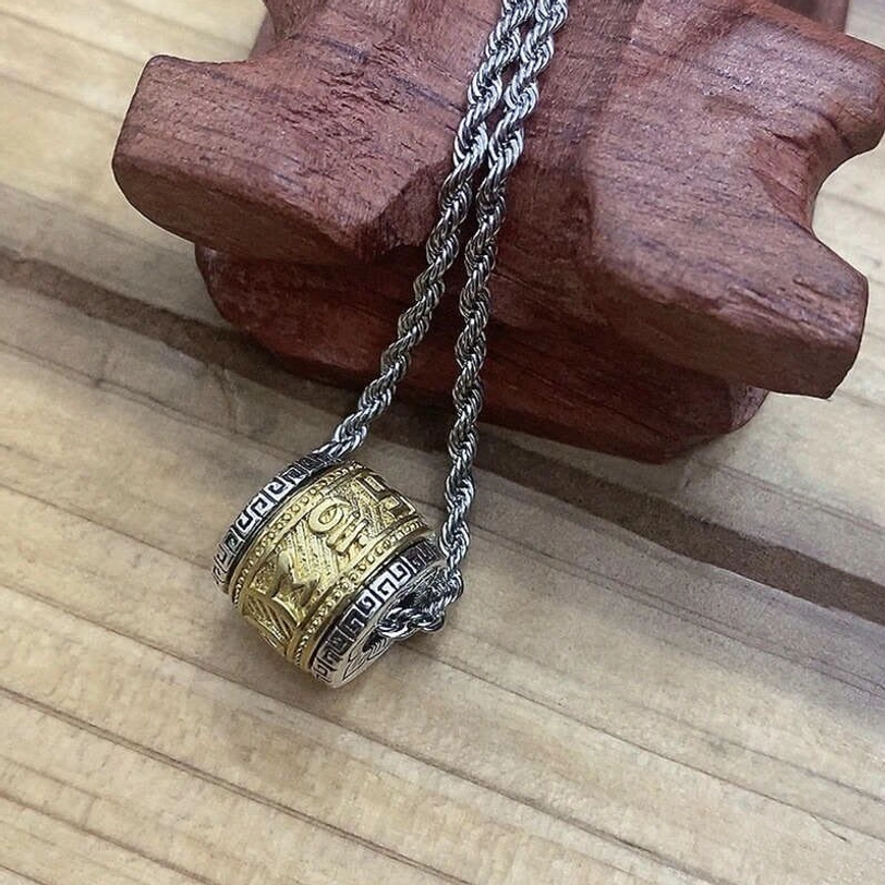 Two-tone gold and silver Tibetan Om Mani Padme Hum barrel pendant necklace with twisted rope chain on wooden display stand