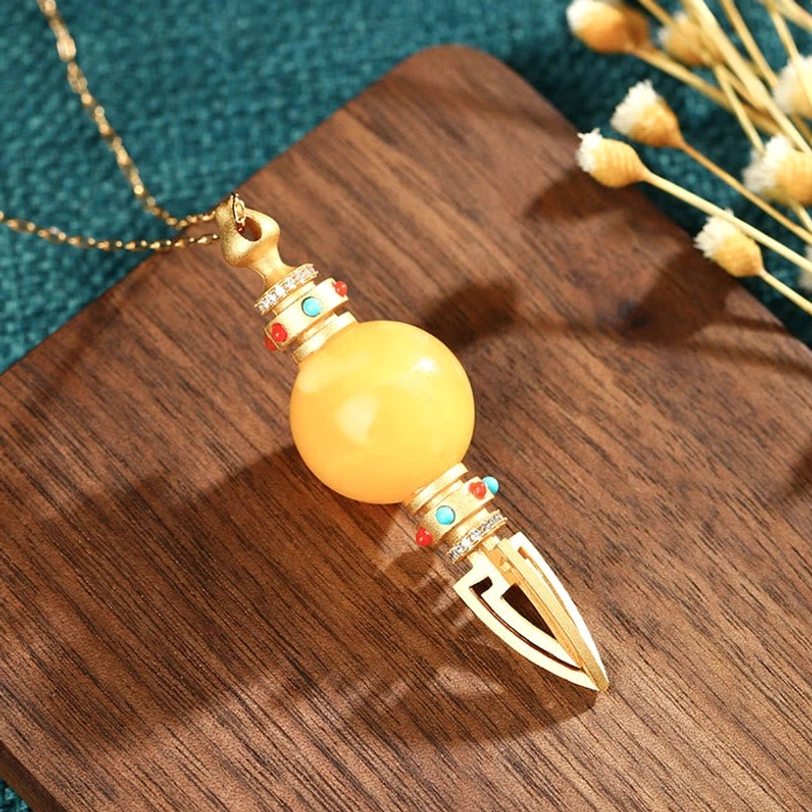 Matte yellow amber vajra pendant with gold metal details, front-top angled view with dried flower styling