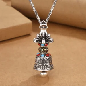 Vintage silver Tibetan Vajra Bell necklace pendant with five-pronged dorje top design and decorative stone accents, photographed from top view on kraft paper
