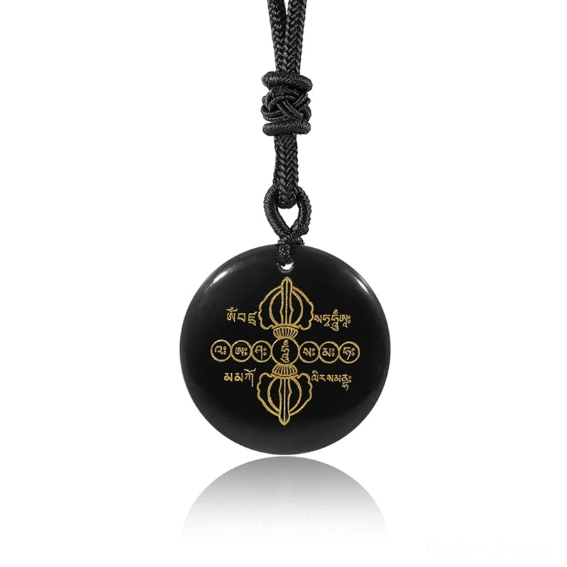 Hanging Vajra Dorje black obsidian Tibetan necklace pendant with golden Sanskrit carvings on white reflective background