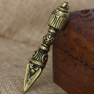 Side view of authentic handmade tibetan vajra dorje showing intricate engraved patterns on the ritual shaft and decorated head, placed on burlap and wooden surface