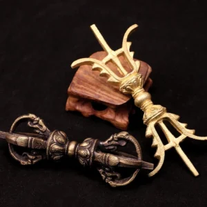 Tibetan Vajra Dorje three-prong and five-prong styles side by side on wooden display stand, showing antique brass and bronze finishes with aged patina