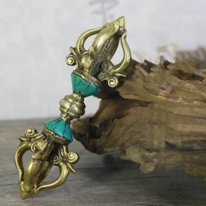 Overhead view of authentic Tibetan copper vajra dorje with turquoise stone accents on wooden surface