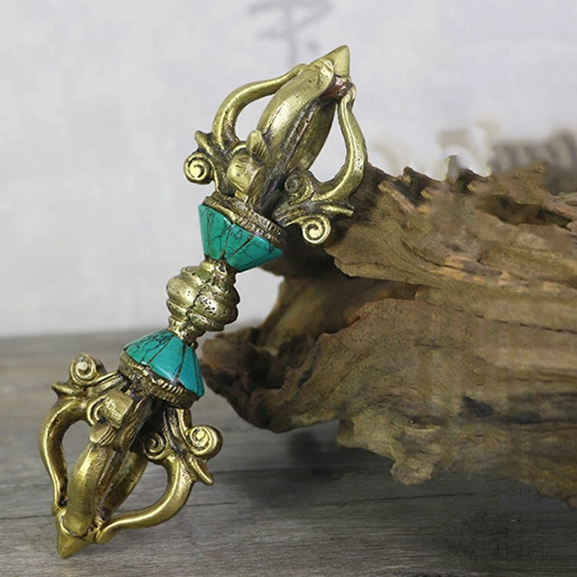 Overhead view of authentic Tibetan copper vajra dorje with turquoise stone accents on wooden surface