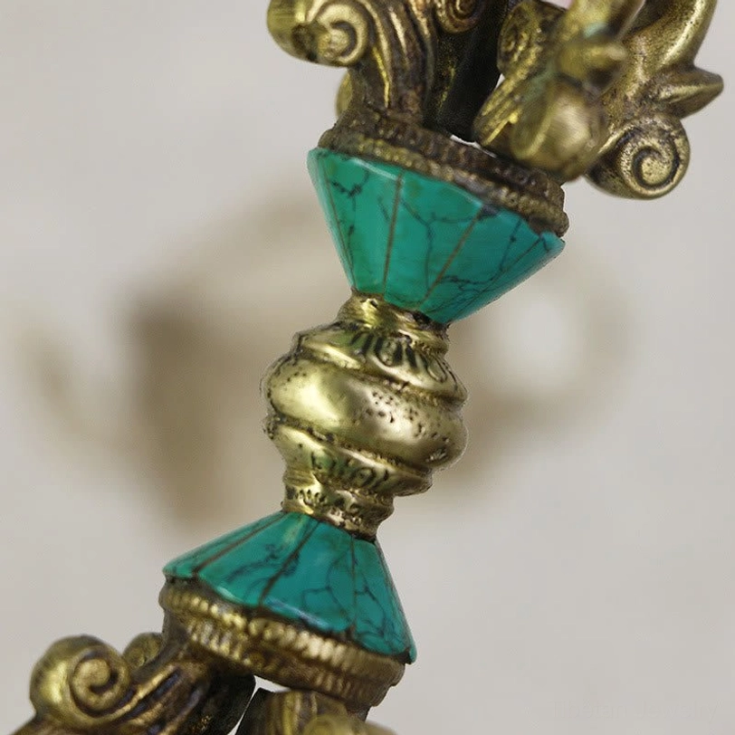 Close-up side view of Tibetan vajra dorje midsection showing stacked turquoise inlays and carved details