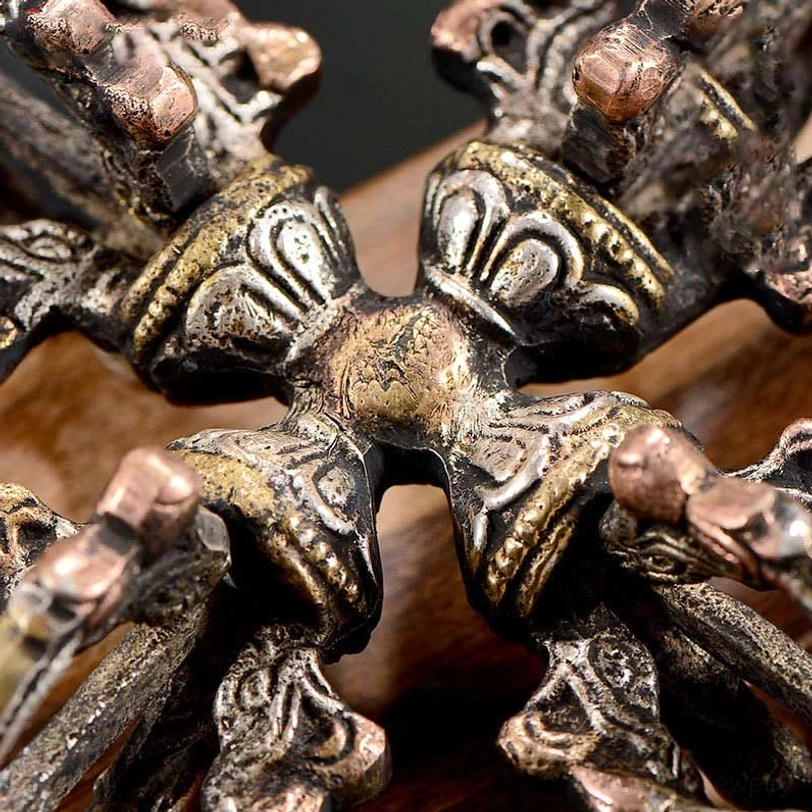 Extreme close-up overhead view of double dorje showing embossed relief patterns and mixed copper-bronze tones